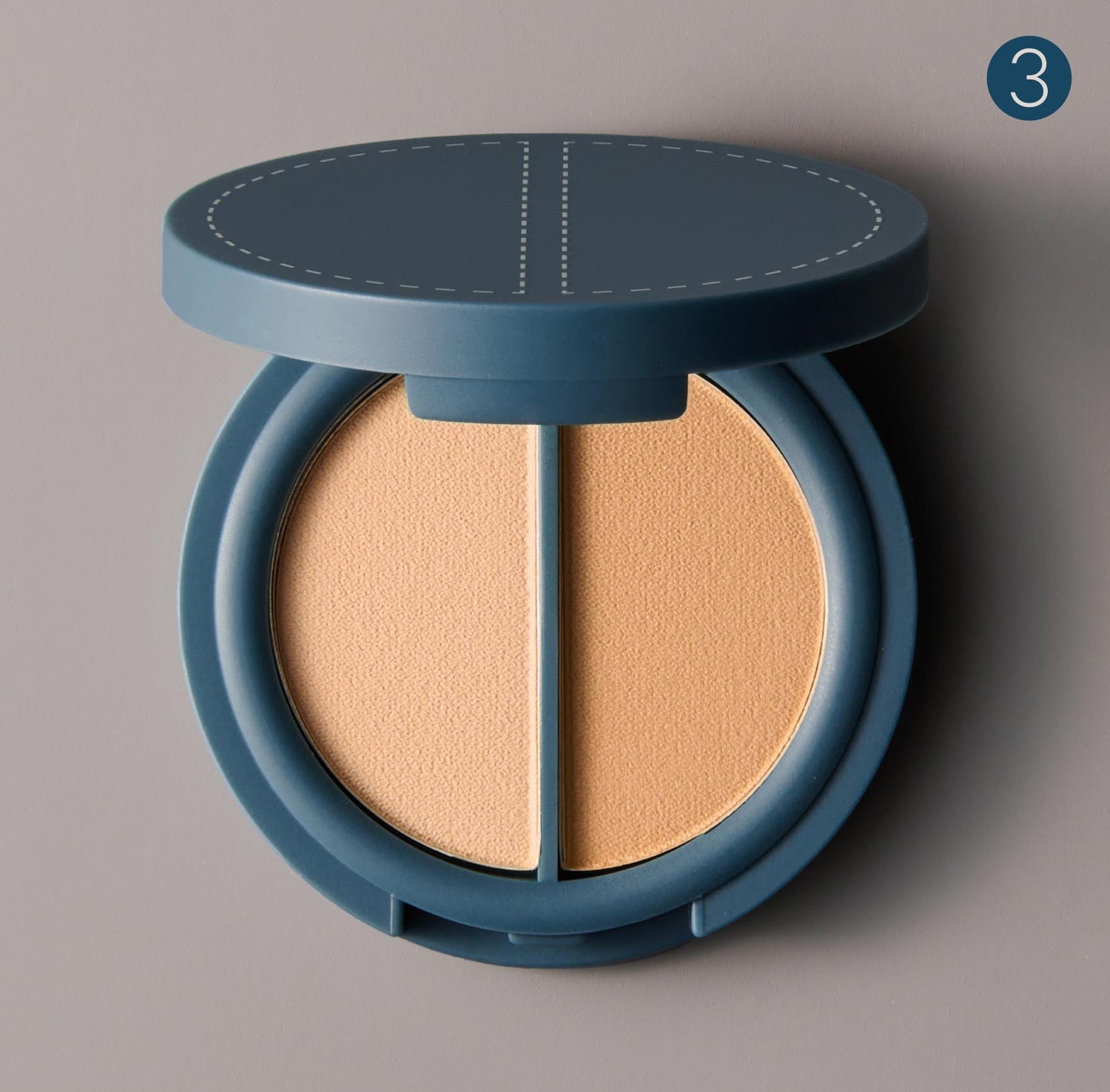 A circular, teal-colored compact of two shades of warm beige-colored pressed cosmetic powder on a gray background. The number 3, in a dark teal-colored circle, sits in the upper right corner of the image.